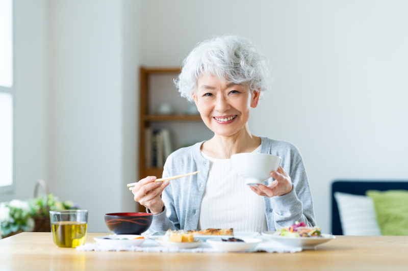 自分に合ったインプラントの歯で美味しく食事をいただく女性