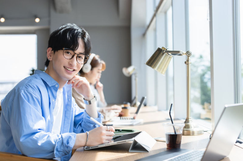 コワーキングスペースで作業する笑顔の男性