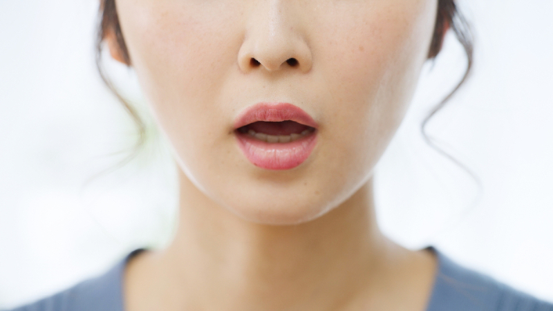 口を開けて息を吐く女性