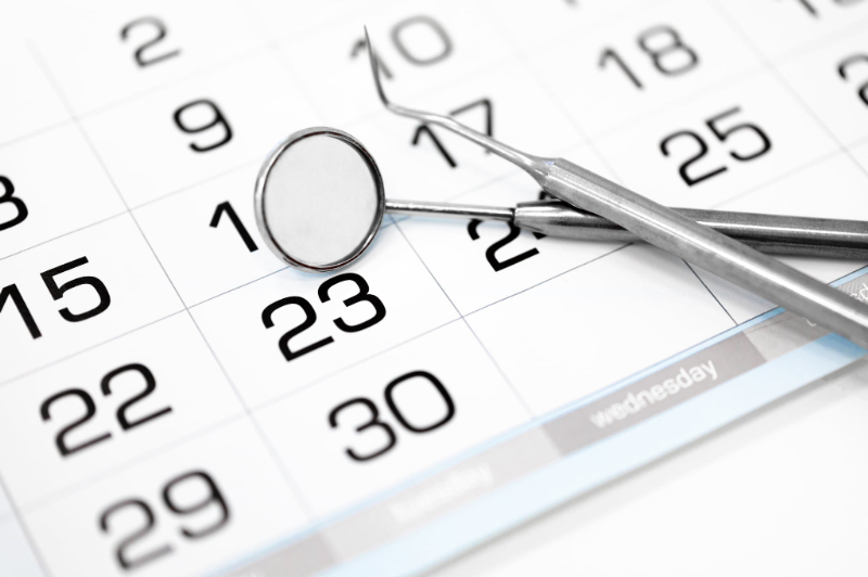 歯医者で歯のクリーニングを受ける理想の頻度を示すカレンダーと医療器具