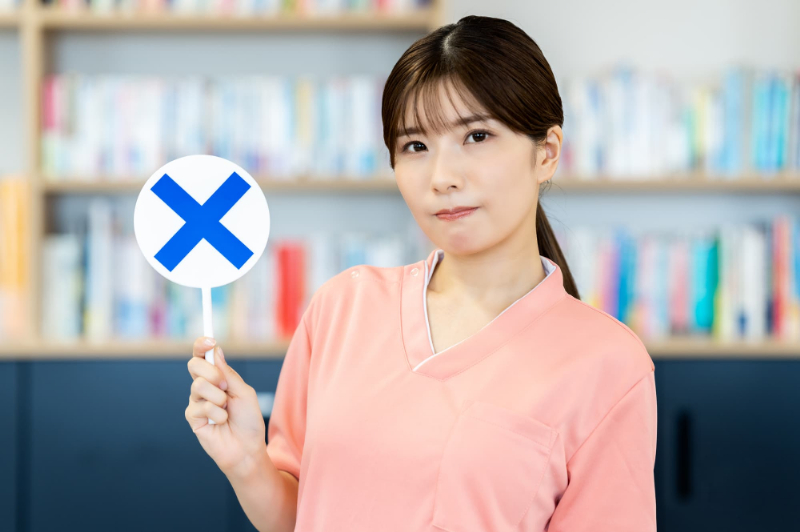 ホワイトニングができない歯についてバツマークを手に持った女性が説明するイメージ