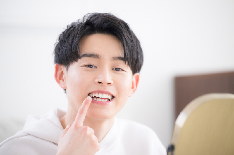 生えてきた親知らずを指さす若い男性