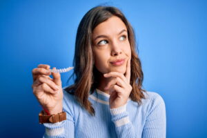 マウスピース矯正で滑舌が悪くなるのはなぜなのかマウスピースを手に考える女性
